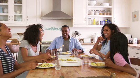 Family With Teenage Children Eating Meal In Kitchen