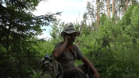 Male traveler in hat on edge of wild forest video call from mobile phone