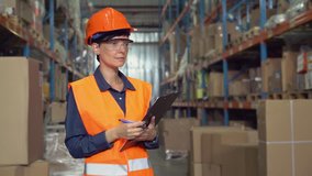 Woman worker standing near metal racks with boxes writing in paper document. Professional young employee in storehouse wearing uniform high visibility orange hard hat and vest. - Powered by Shutterstock - Get 15% off with code: PIKWIZARD15