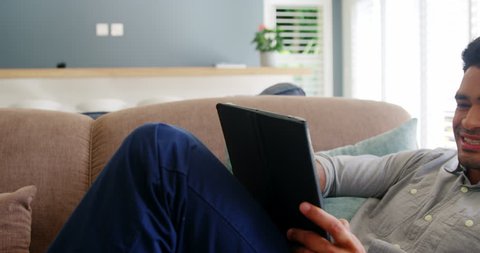 Happy man using digital tablet in living room at home