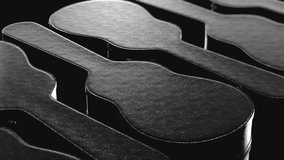 Seamlessly looping pan over a line of black leather hard guitar cases. Presented with high contrast lighting and a shallow depth of field. This video is a 3d render.