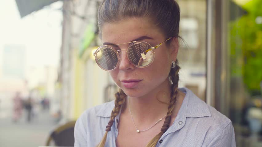 Close up portrait of young woman in sunglasses against cityscape
