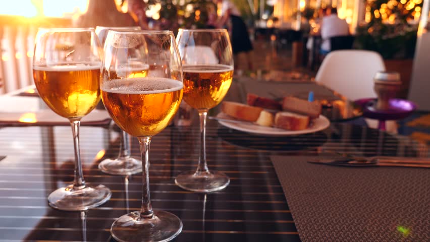 Friends clink glasses with alcohol in a restaurant by the sea. close-up. slow motion