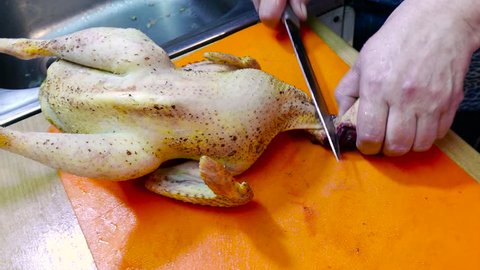 the woman at home in the kitchen cut off the bird's head, then cuts the beak and head in half and cuts the tuft