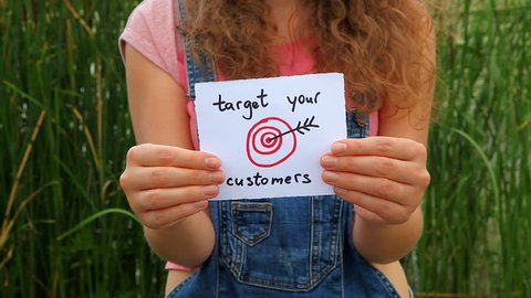 Target your customers - woman show words with painted target as business concept