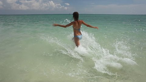 Young woman running into tropical sea