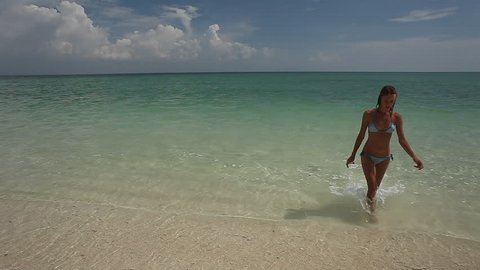 Young woman coming back to a beach after swimming in tropical sea
