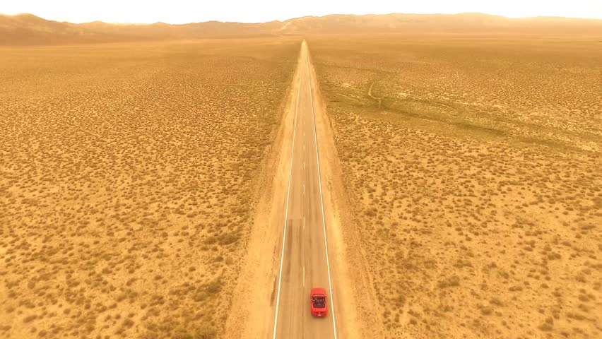 Aerial view of a desert road in Nevada of a red convertible with no other people around.