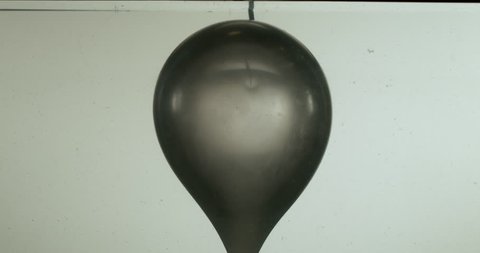 Grey Balloon Pops Underwater Slo-Mo - A grey balloon pops underwater, creating a large balloon-shaped mass of air that rises to the surface and causes a splash Stock Video