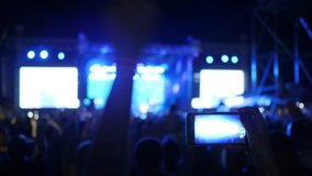 people waving hands on rock concert, fan person records video and takes pictures on android, at concert party, cellphone in hand makes photo of illuminated stage at festival of live music,