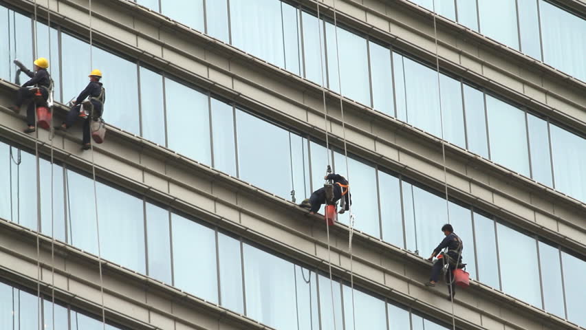 Climber cleaning modern building glass wall