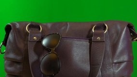 4k Travel concept with woman placing passport into carry bag and carrying it away, against green screen, closeup. 