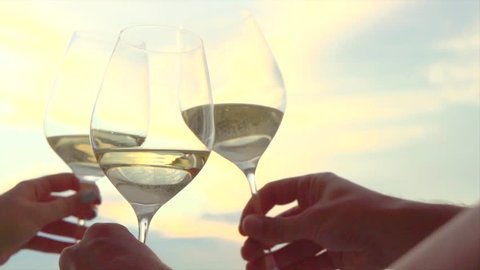 People holding Glass of Wine, Making a toast over Sunset sky. Birthday. Friends drinking White Wine, toasting. Clink. Party outdoors. Enjoying time together. Slow motion 240 fps 4K UHD video