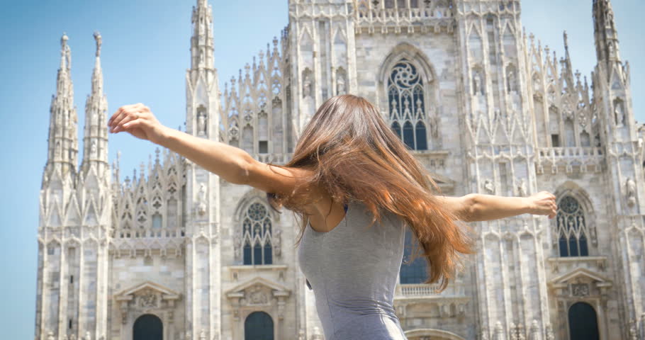 Beautiful young tourist girl (woman) in Milan, feels free, happy smiling, the backdrop of the Milan cathedral. Concept: tourism, love to travel, communication, freedom, love life, a big city.