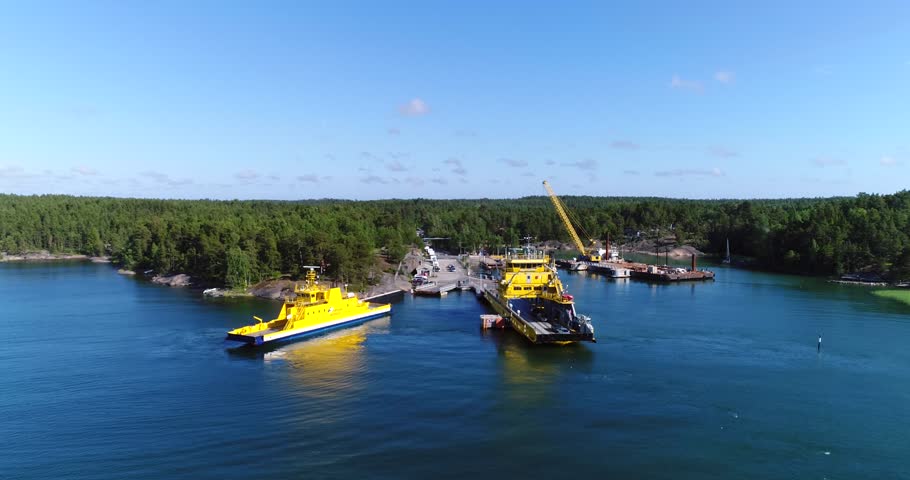 KORPPOO, VARSINAIS-SUOMI, FINLAND - JULY 03: Cinema 4k aerial view over two cable ferrys and a car queue, heading to houtskar and kokar, on a sunny summer day, in the finnish archipelago