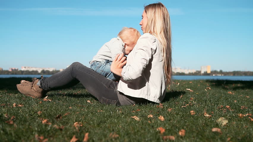 Baby playing with mother on the grass in park