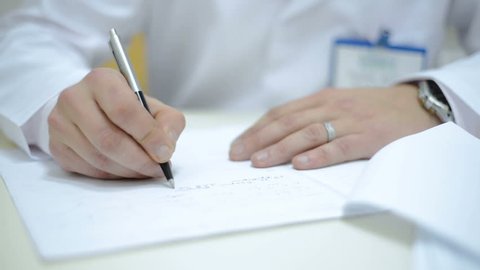 Close Up Caucasian male Doctor hand writing rx prescription