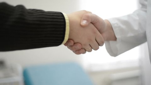 qualified Doctor and Grateful patient shaking hands. handshake, healthcare services at clinic.
