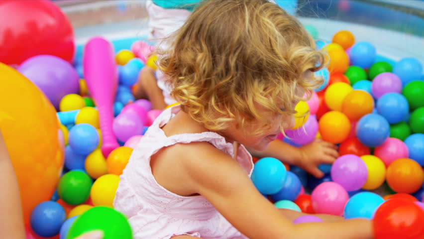 Laughing pre school Caucasian girl in forefront having fun playing with sister ethnic friends in multi coloured ball pool shot on RED EPIC Royalty-Free Stock Footage #2876914