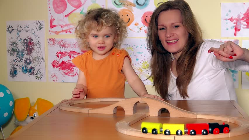 Playful family girls mom and little lovely daughter girl pushing wooden train together. Static closeup shot. 4K UHD Royalty-Free Stock Footage #28770475
