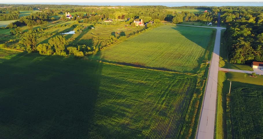 Scenic rural Wisconsin farm fields with long shadows at sunrise, aerial view.