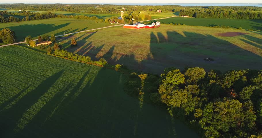Scenic rural Wisconsin farm fields with long shadows at sunrise, aerial view.