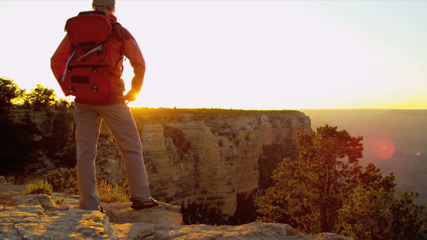 Lone female hiker watching the sun setting over the canyons, USA, Shot on Red Epic
