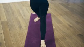 Front view of a beautiful young woman doing yoga asanas indoors. She is wearing black clothes and using a rug. Locked down real time medium shot