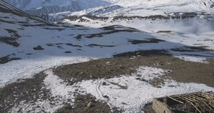 Aerial drone backwards ascending pan up reveal of high altitude Himalayan snow-capped mountain peaks and landscape around holy Tilicho Lake in Nepal. 4k 1.9:1 23.976fps
