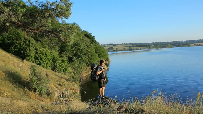 Man traveler with backpack hiking on a hill