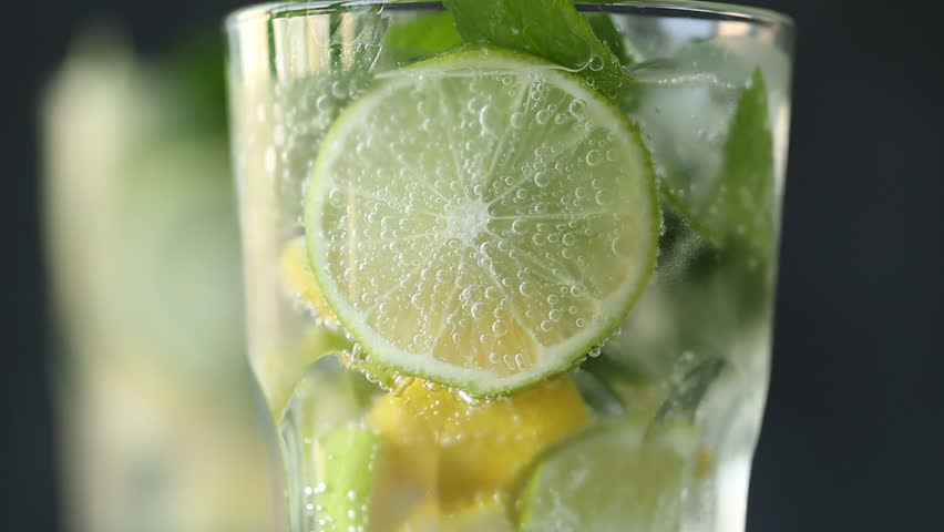 Mineral water in the glass with ice cubes,mint, lime and lemon slices on black background | Shutterstock HD Video #28793437