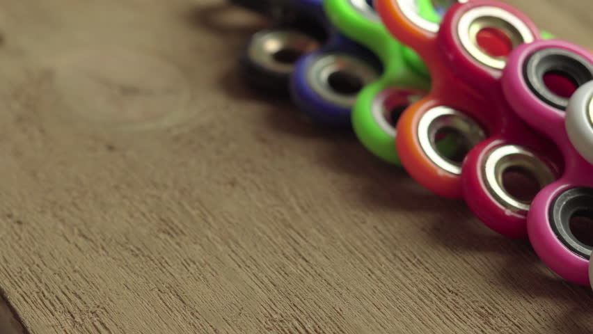 Colored fidget spinners stress relieving toy on wooden background.