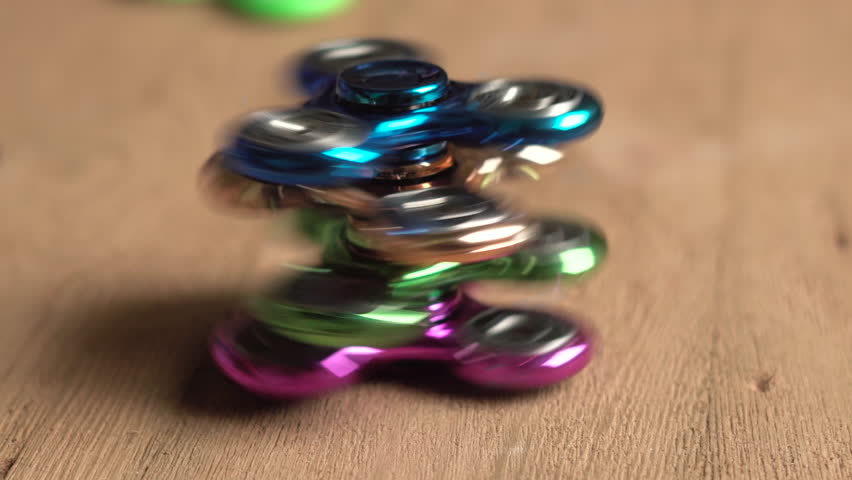 Set of colored fidget spinners stress relieving toys rotating on wooden background