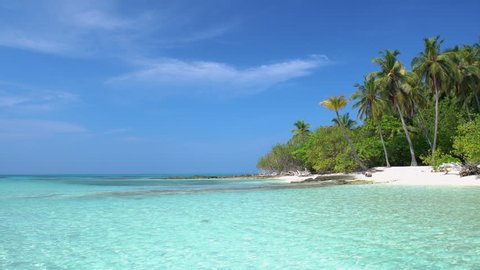 Tropical island at maldivian atoll in Indian Ocean. Wild and uninhabited coast with palm trees. Travel destinations
