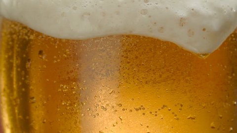Glass of beer close-up with froth in slow motion