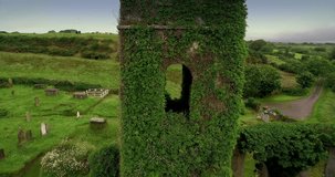 Aerial drone view of flying over Irish Estuary to an abandoned church covered in vines