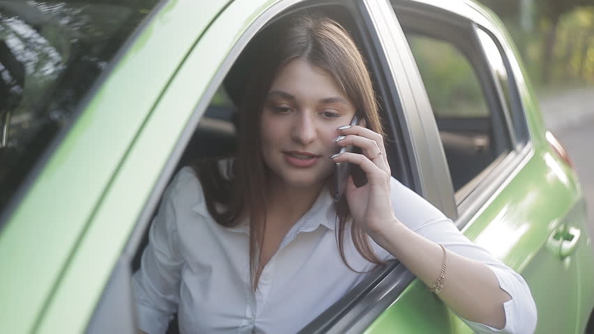 Close up of girl sitting in the car downing a window, using a phone and smiling | Shutterstock HD Video #28809787