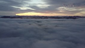 Flying above the clouds during sunrise. Moving down into white mist.