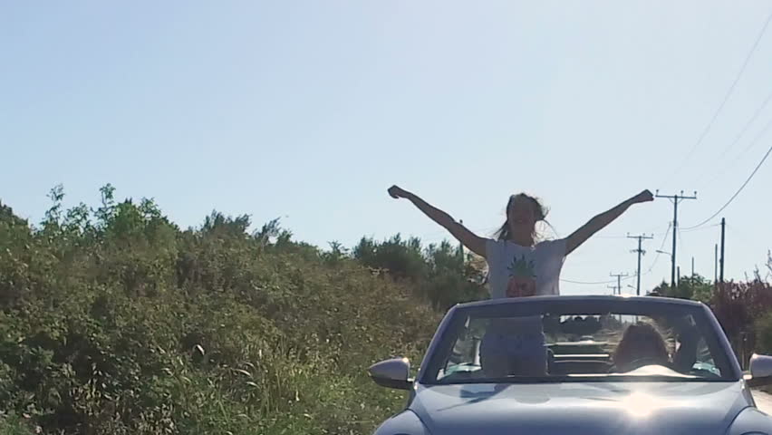 Girls enjoying the ride in a convertible car, summer, slow motion