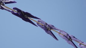 Clothes line against blue sky close-up 4K 2160p 30fps UltraHD footage - Purple pegs in a row 3840X2160 UHD video