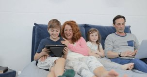 Family Spend Morning Together On Bed Parents With Children Using Tablet And Laptop Computer In Bedroom Slow Motion 60