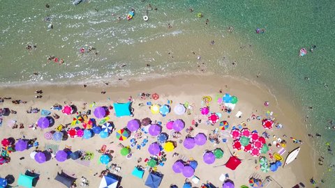 Beautiful sandy beach with people and colorful umbrellas - Top down aerial footage