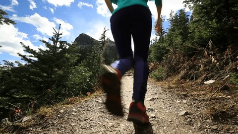 Young sportive woman trail running in nature. Female running on mountain trail. Cross country