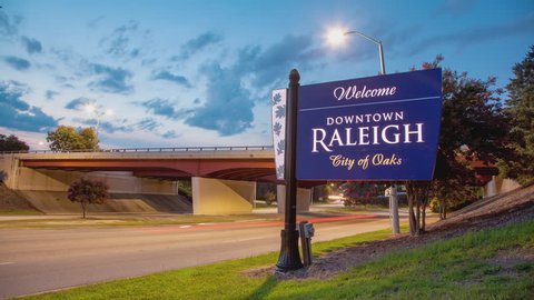 Welcome to Downtown Raleigh - City of Oaks Sign Timelapse with Passing Vehicle Traffic Driving at Sunset during the Summer in North Carolina
