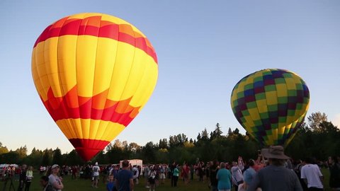 June 25th, 2017, 5:45 am Tigard Festival of Balloons, Cook Park, Tigard Oregon. Hot air balloons stand ready to lift off, in the early morning light, as crowds of the public look on.