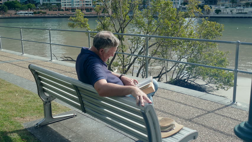 A middle aged male tourist sitting reading and relaxing in Brisbane which is the capital of Queensland Australia.
