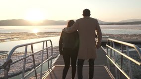 Frozen but happy couple in love walks on the pier at sunset stock footage video