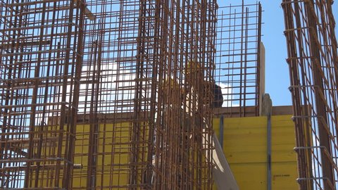 wire armature on construction site with workers,
Handheld camera Balanced Steady shot 