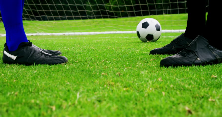 Two football players shaking hands in the field
