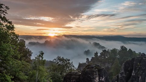 Stunning time lapse over the Saxon Switzerland in Germany - cloudy sky and sunrise over the green landscape with beautiful blue horizon
